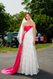 Robe de mariée Promesse Fuchsia Ousman O. en dentelle de soie et crêpe de soie, avec pan de soie fuchsia formant un cœur sur le côté, applications de dentelle, détails nacrés et voile en soie.