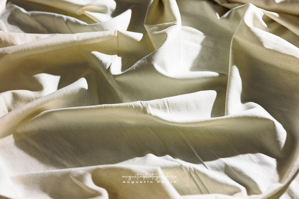 Main manipulant un textile naturel dans l'atelier Ousman O. – matière, création responsable et savoir-faire artisanal.